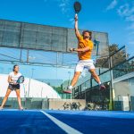 Mixed padel match in a blue grass padel court – Beautiful girl and handsome man playing padel outdoor